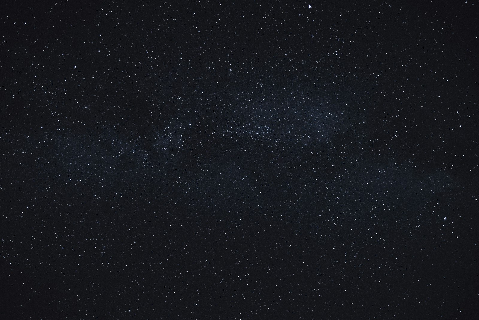 A faint, barely-there band of the Milky Way across a deep grey-blue sky scattered with stars.