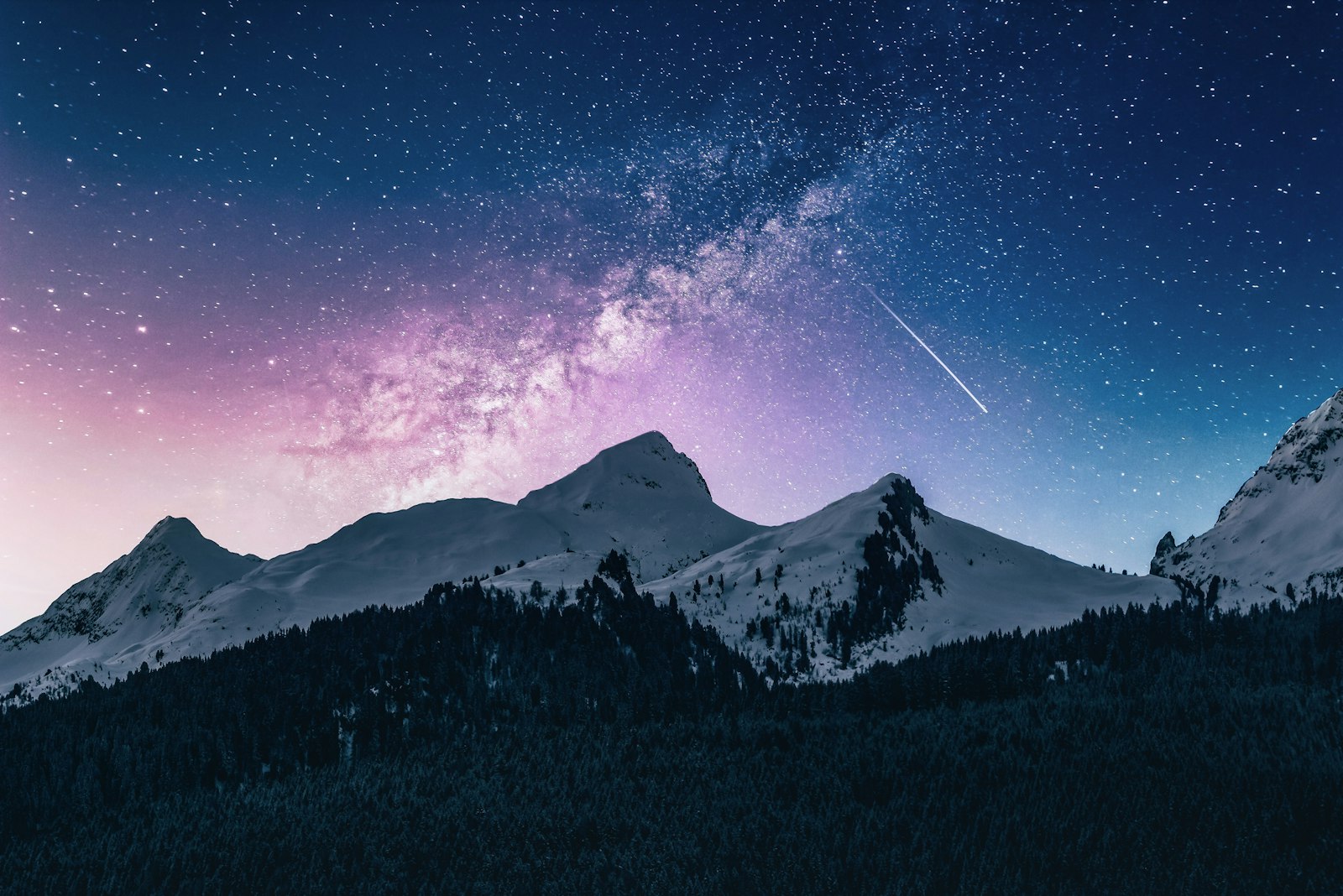 The Milky Way and a shooting star above snow-dusted mountain peaks, the sky glowing soft pink near the horizon.